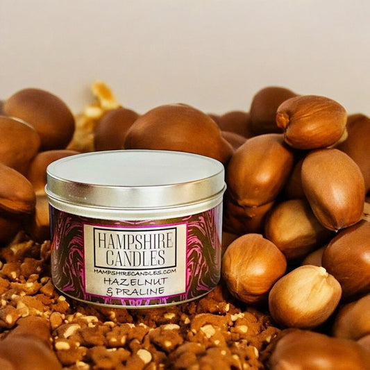 Hazelnut & Praline Candle Burning on a Cozy Tabletop – A warm, flickering candle in a compact tin, filling the room with sweet, nutty, and spiced fragrance.