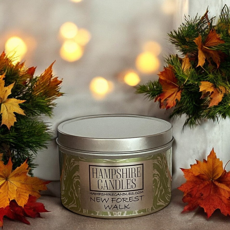 The "New Forest Walk" scented candle displayed alongside forest-themed decor, such as green plants and wooden accents, complementing its fresh, pine-scented fragrance. The overall scene evokes the peaceful serenity of a woodland walk, bringing the outdoor