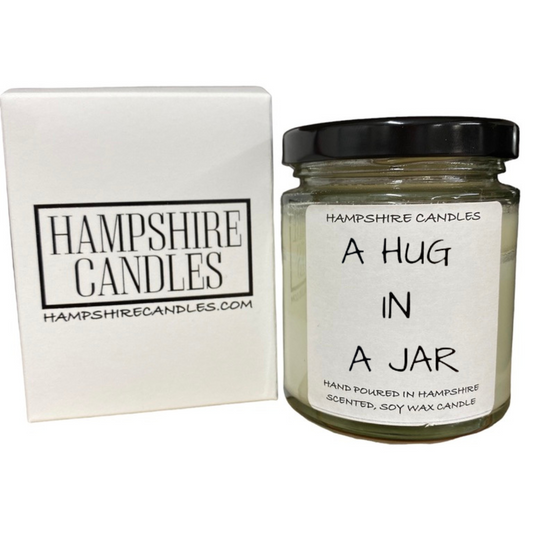 "Luxury scented candle with 'Hug in a Jar' text on the front, available in calming fragrances like Sea Breeze and Fresh."