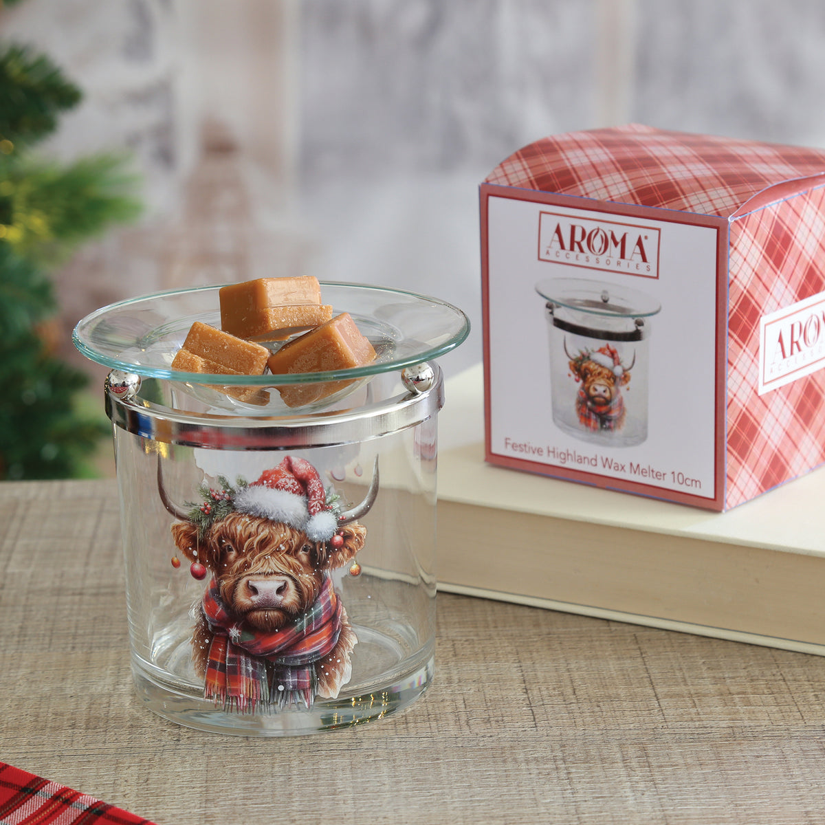 Festive Highland cow glass wax melt burner holding wax melts, beside its red tartan gift box