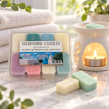 Clean & Fresh soy wax melts beside folded white towels and a lit ceramic burner, with cream and mint green melts in front