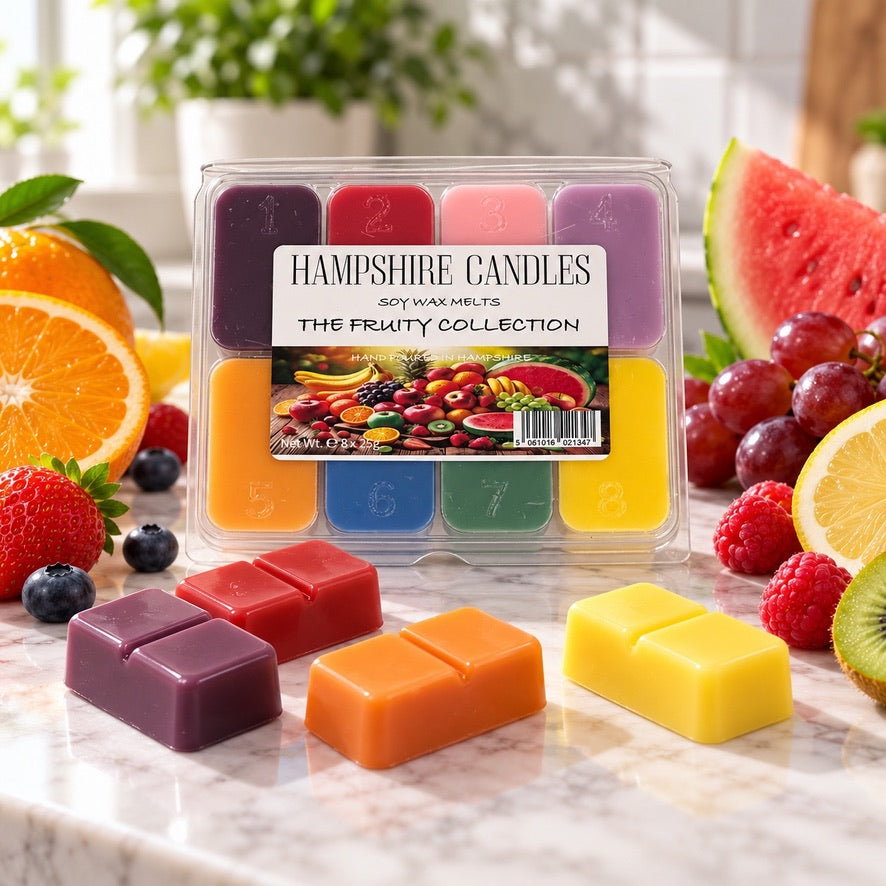 Fruity Collection selection box with fresh oranges, watermelon, grapes and berries, and loose plum, orange and yellow melts