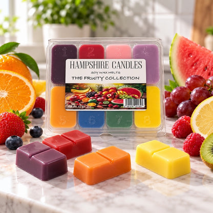 Fruity Collection selection box with fresh oranges, watermelon, grapes and berries, and loose plum, orange and yellow melts