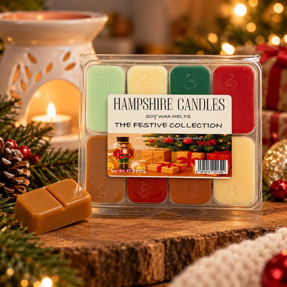 Cosy Christmas scene: Festive Collection wax melt box on a log slice with a lit tealight burner, pine sprigs and baubles