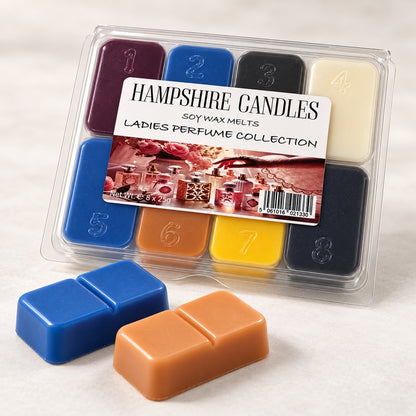 Perfume Collection wax melt selection box angled on marble with two loose snap melts, one royal blue and one caramel orange