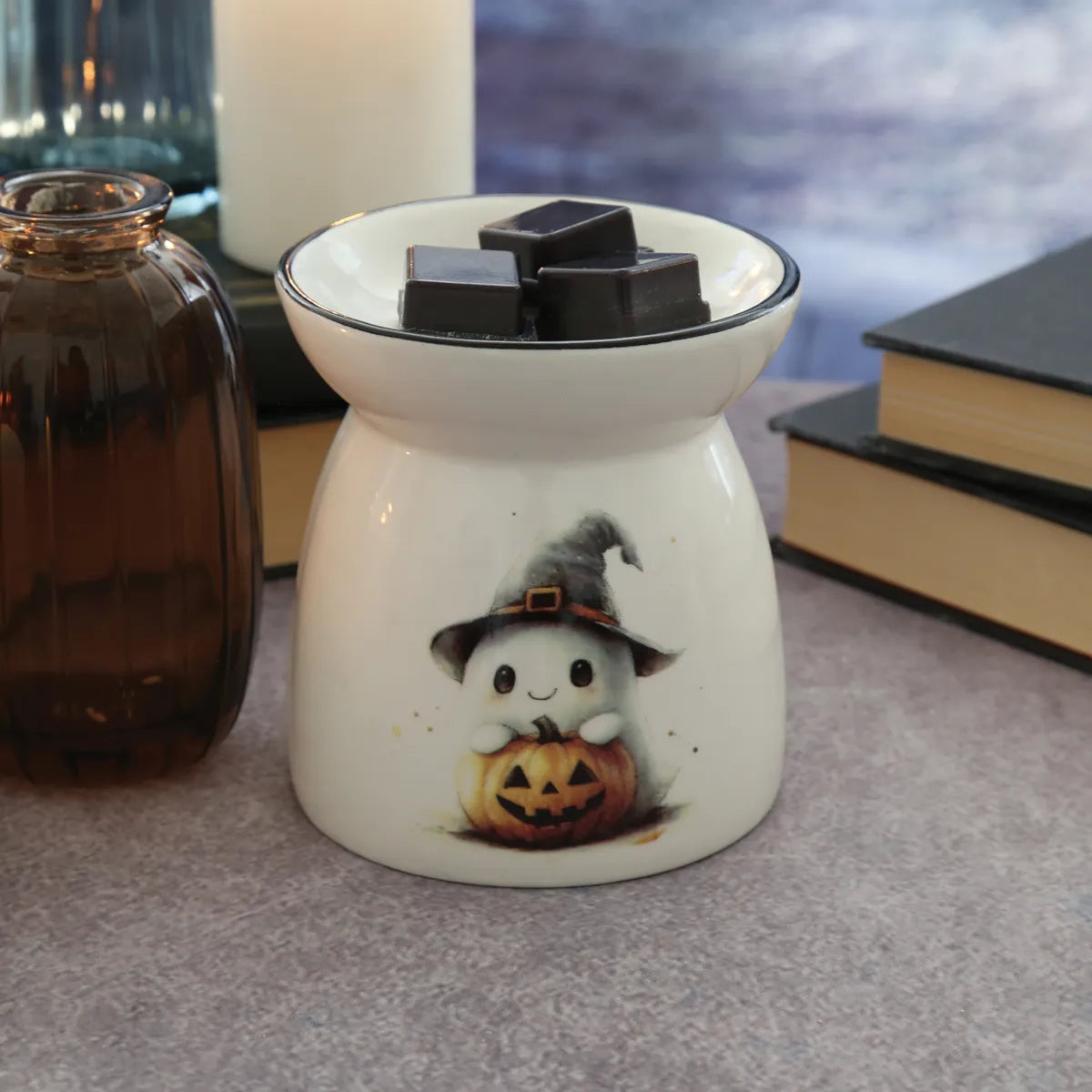 Close-up of Halloween Ghost Wax Melt Burner showing the cute white ghost holding a pumpkin and wearing a black witch’s hat.