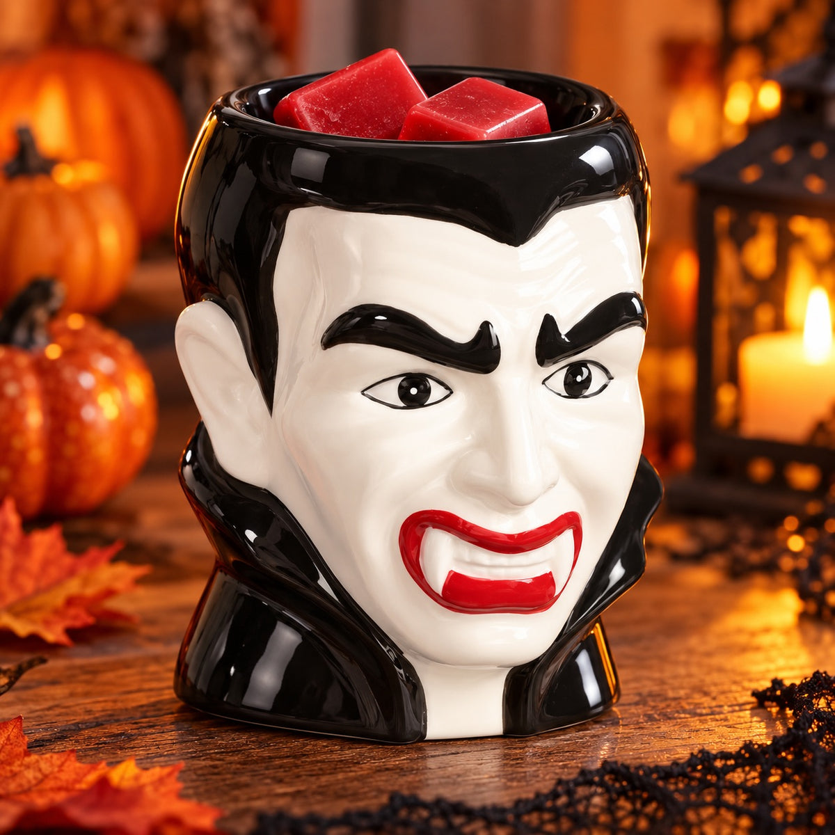 Dracula wax melt burner with red wax melts in a cosy Halloween setting with pumpkins and autumn leaves