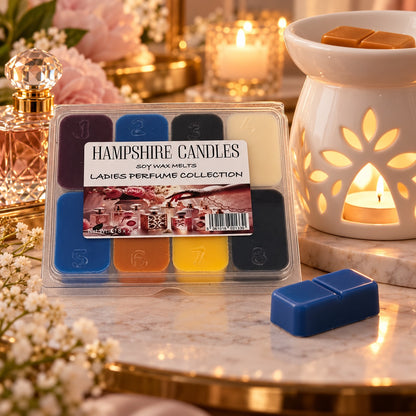Cosy scene with the Perfume Collection wax melt box, a loose blue melt and a lit white ceramic tealight burner warming wax