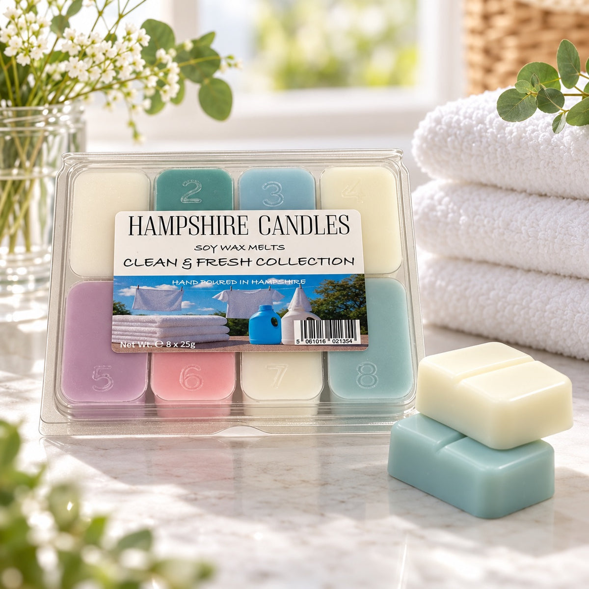 Clean & Fresh Collection selection box on marble with stacked cream and blue-green melts, white towels and gypsophila