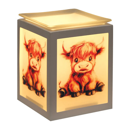 Highland Calf electric wax melt burner illuminated in a cosy home while gently warming scented wax melts in the glass dish.