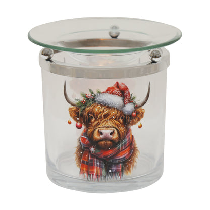 Glass Highland cow Christmas wax warmer lit by a tealight, showing the cow artwork
